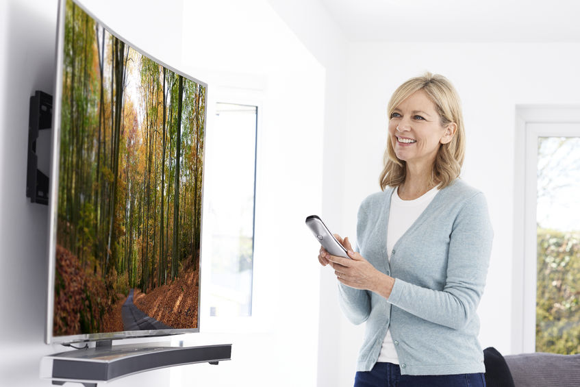 Mature Woman With New Curved Screen Television At Home